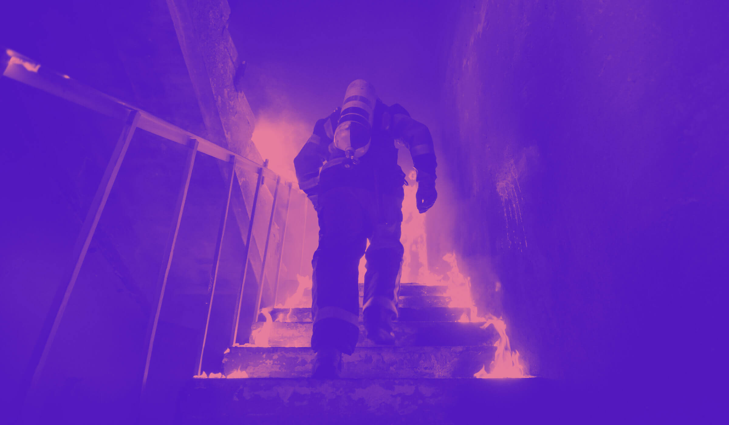 Fireman running up a flight of burning stairs