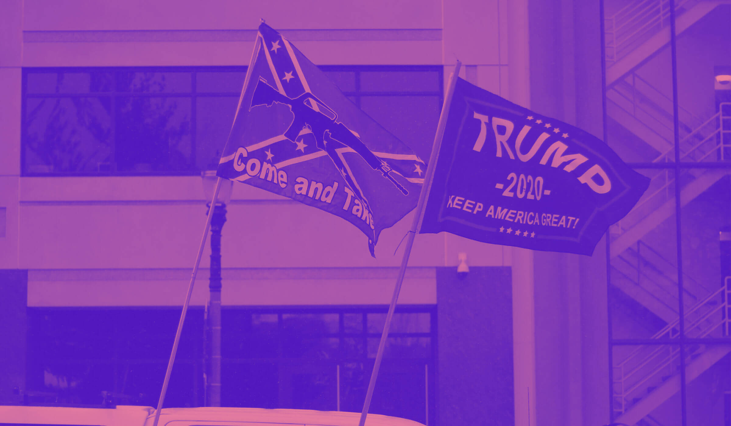 A confederate flag and Trump 2020 campaign flag wave at a right wing protest in Michigan amid the COVID-19 / novel coronavirus pandemic in April 2020