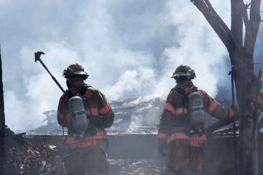 firemen in front of smoldering rubble