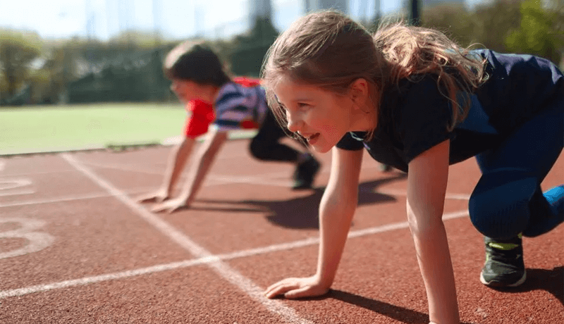 Kids lining up on a track preparing to run a race
