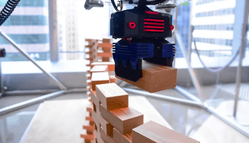 CU-Brick, a cable-driven robot, building a wall with wooden blocks in a well-lit room