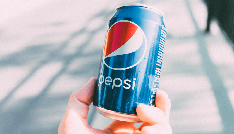A hand holding a can of Pepsi on a bright day